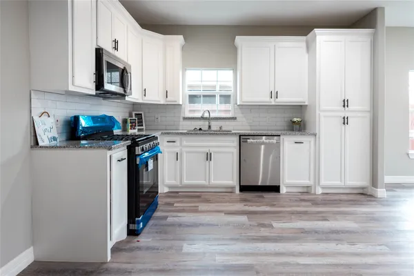 a kitchen with granite countertop a stove a sink and a microwave