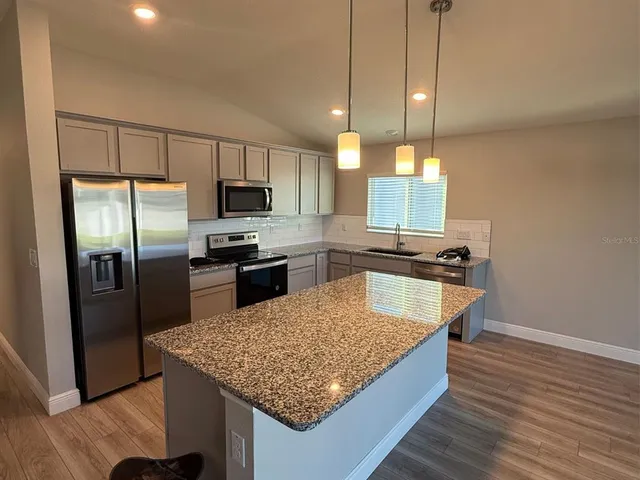 a kitchen with kitchen island a counter space a sink appliances and cabinets