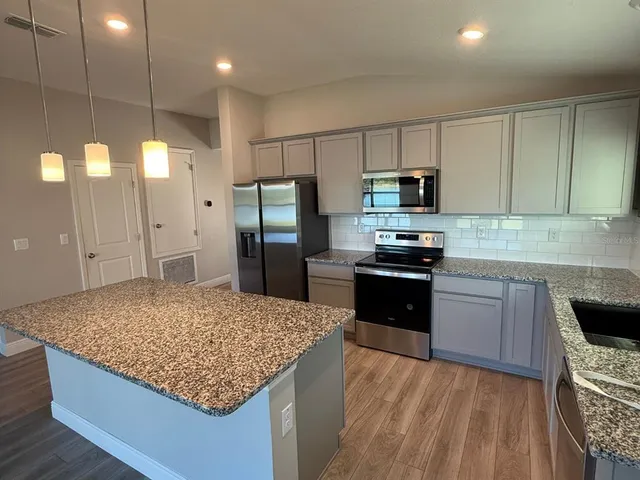 a kitchen with granite countertop a refrigerator a stove and a sink
