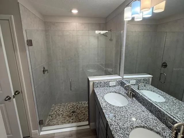 a bathroom with a granite countertop sink a mirror a vanity and a shower