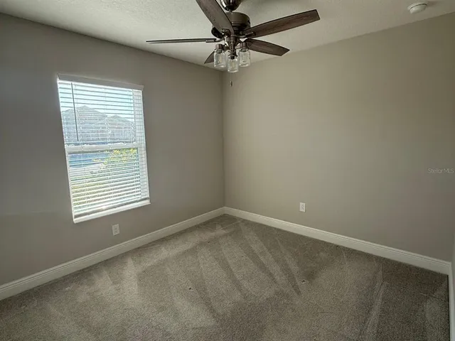 an empty room with a window and a fan