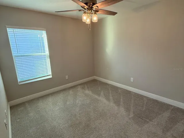 an empty room with a window and a fan