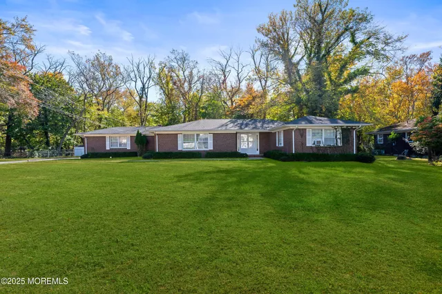 a view of house with yard and trees in the background