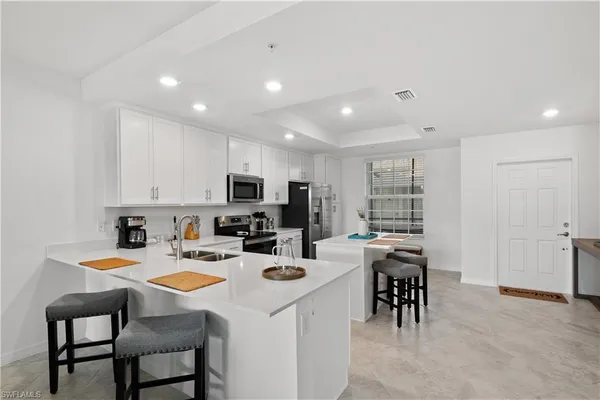 a kitchen with appliances cabinets and chairs