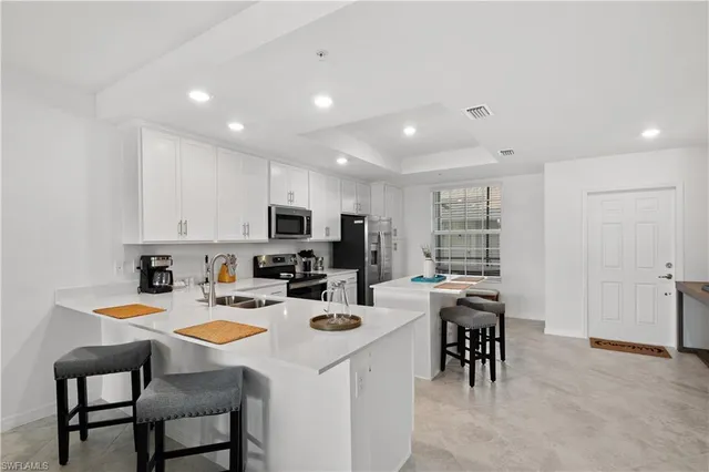 a kitchen with appliances cabinets and chairs