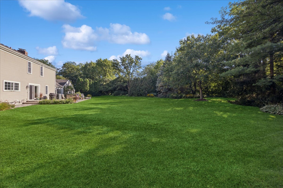 415 Hamilton Drive Wheaton, IL 60189 - Photo 23 of 27 a view of a white house in front of a big yard with plants and large trees