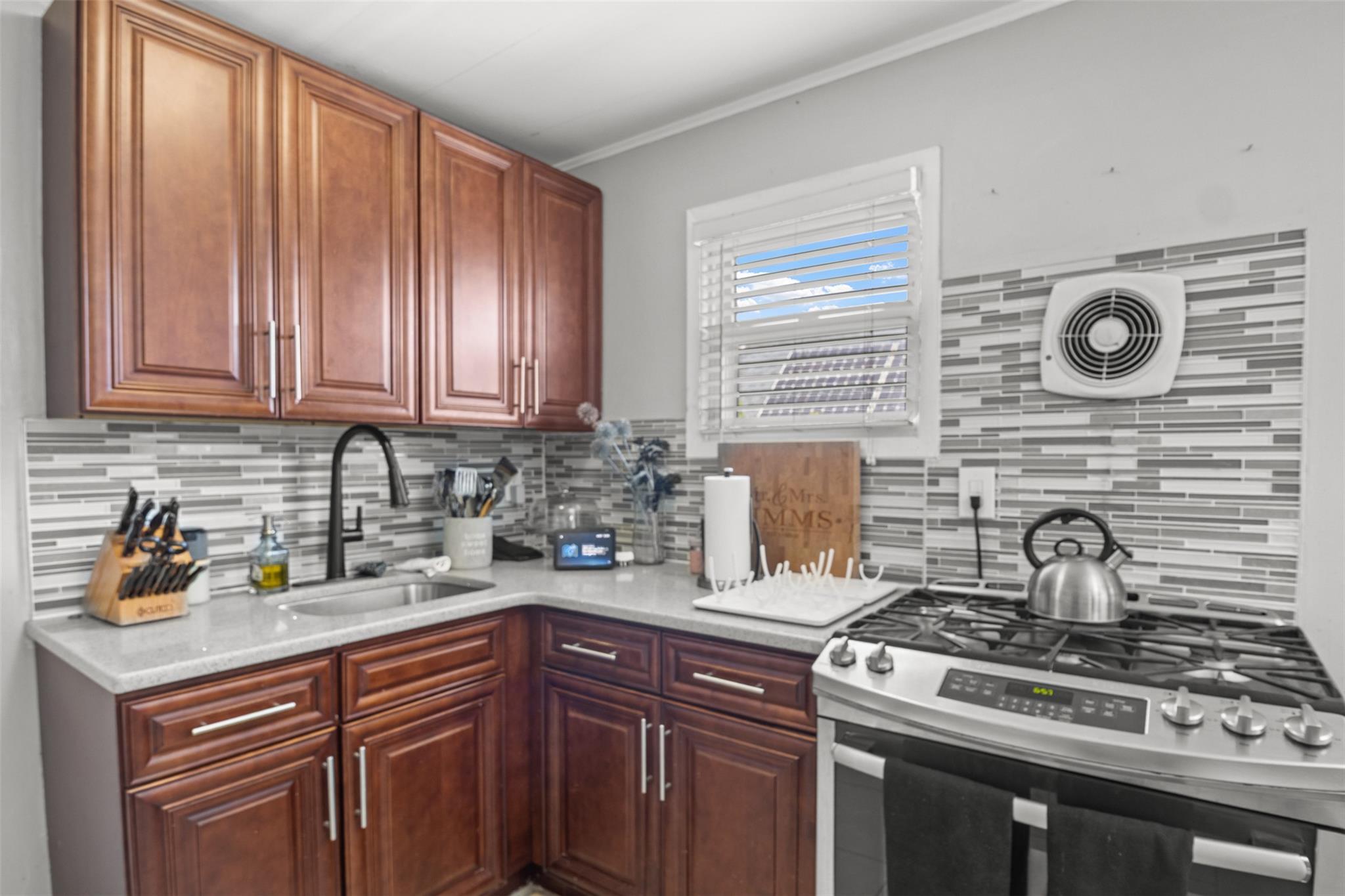 239-15 147th Road Queens, NY 11422 - Photo 20 of 28 Kitchen with stainless steel range with gas cooktop, backsplash, and crown molding