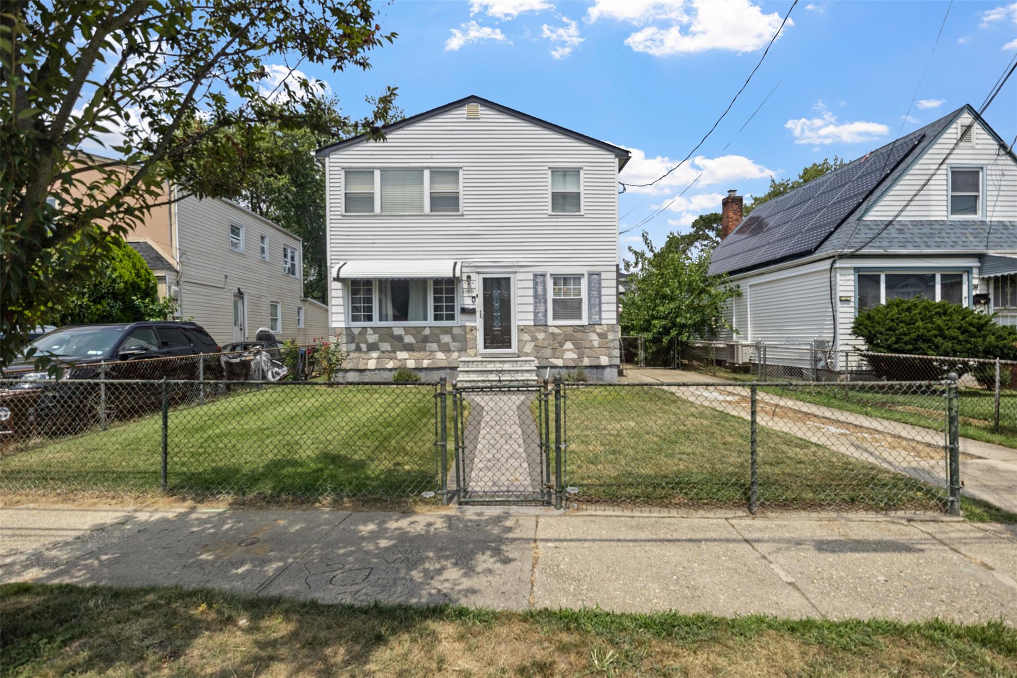 239-15 147th Road Queens, NY 11422 - Photo 25 of 28 Traditional-style house featuring a gate, stone siding, and a fenced front yard