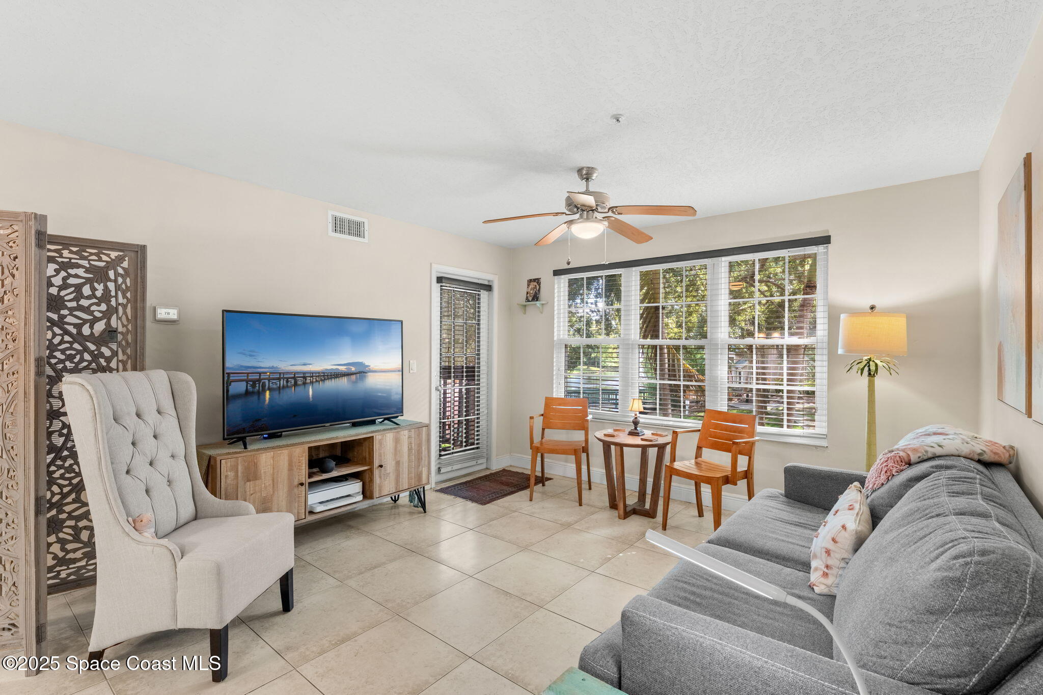 7667 North Wickham Road, Unit 514 Melbourne, FL 32940 - Photo 2 of 37 a living room with furniture a flat screen tv and large window