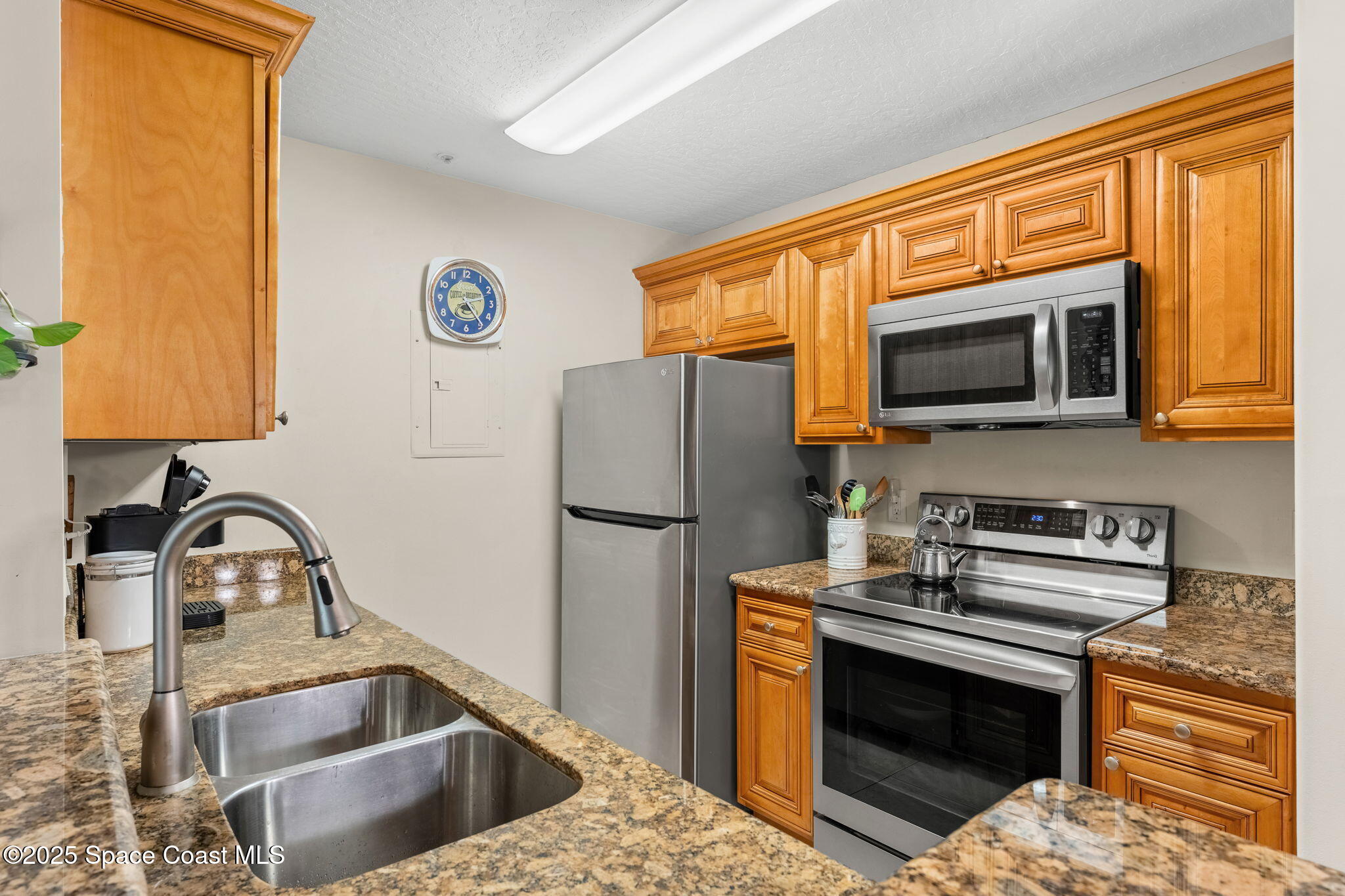 7667 North Wickham Road, Unit 514 Melbourne, FL 32940 - Photo 3 of 37 a kitchen with a sink a microwave a refrigerator and a stove top oven