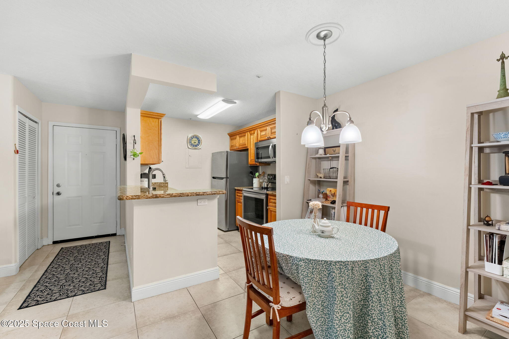 7667 North Wickham Road, Unit 514 Melbourne, FL 32940 - Photo 6 of 37 a kitchen with stainless steel appliances kitchen island granite countertop a dining table chairs and a refrigerator