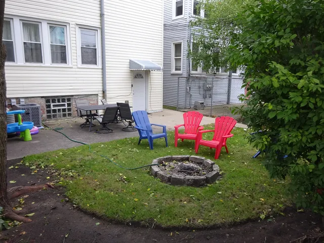 a view of a backyard with table and chairs potted plants and large tree