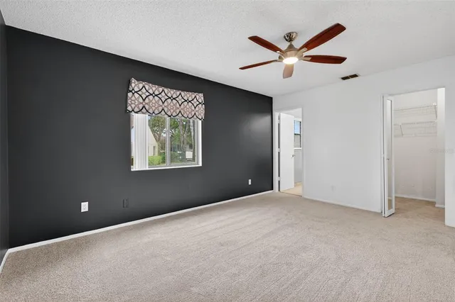 an empty room with window and ceiling fan