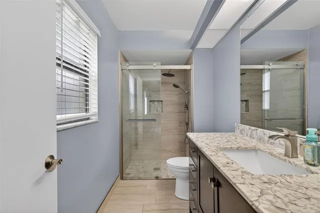 a bathroom with a granite countertop sink a toilet and shower