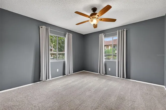 an empty room with window and ceiling fan