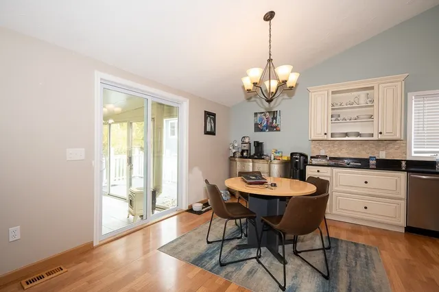 a dining room with wooden floor a chandelier a wooden table and chairs