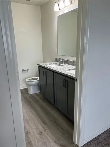 a bathroom with a granite countertop sink toilet and mirror