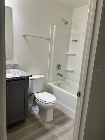 a bathroom with a granite countertop toilet a sink and a bathtub