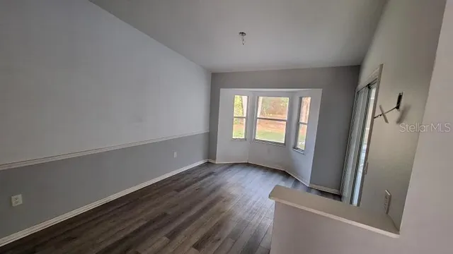 a view of an empty room with a window and wooden floor