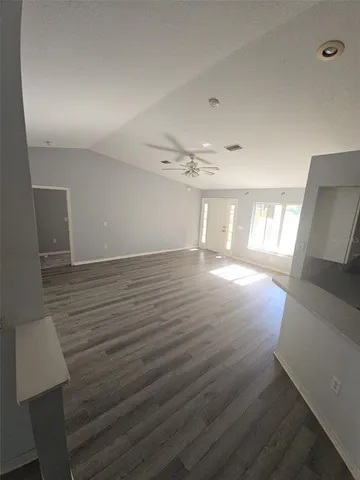 a view of empty room with wooden floor and fan