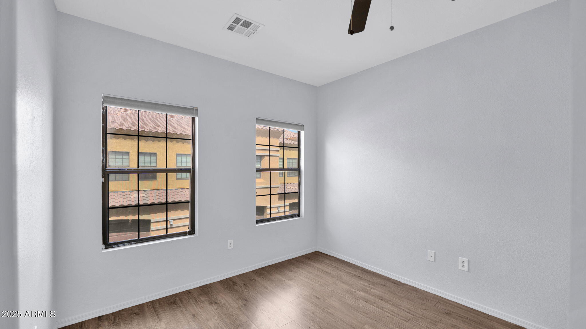 1702 East Bell Road, Unit 113 Phoenix, AZ 85022 - Photo 26 of 32 a view of an empty room with wooden floor and windows