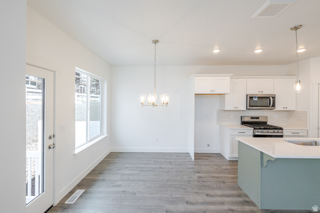 4741 Olive Avenue, Unit 406 Mapleton, UT 84664 - Photo 5 of 20 Kitchen featuring two tone color scheme, stainless steel appliances, a chandelier, decorative backsplash, and light wood finished floors