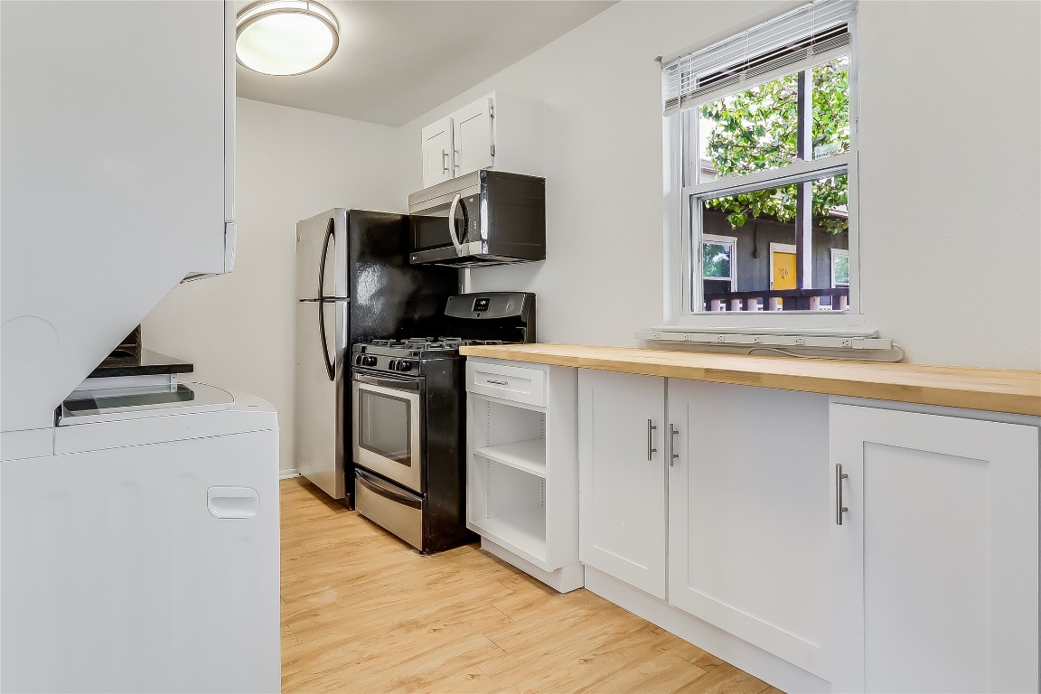 2401 Manor Road, Unit 210 Austin, TX 78722 - Photo 10 of 20 a kitchen with white cabinets stainless steel appliances and window