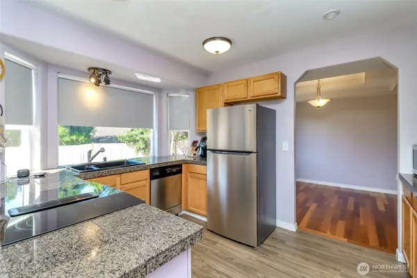 a kitchen with stainless steel appliances granite countertop a refrigerator a sink and wooden cabinets