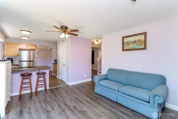 a living room with stainless steel appliances furniture and a wooden floor