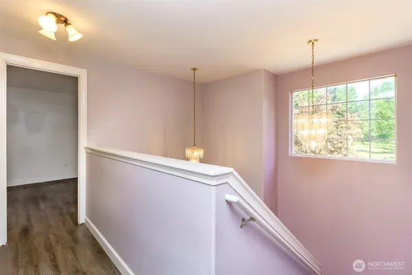 a view of a hallway with wooden floor and staircase