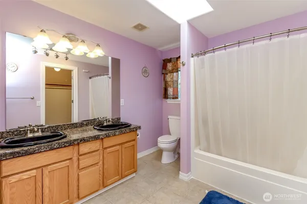 a bathroom with a granite countertop sink a toilet a mirror and shower