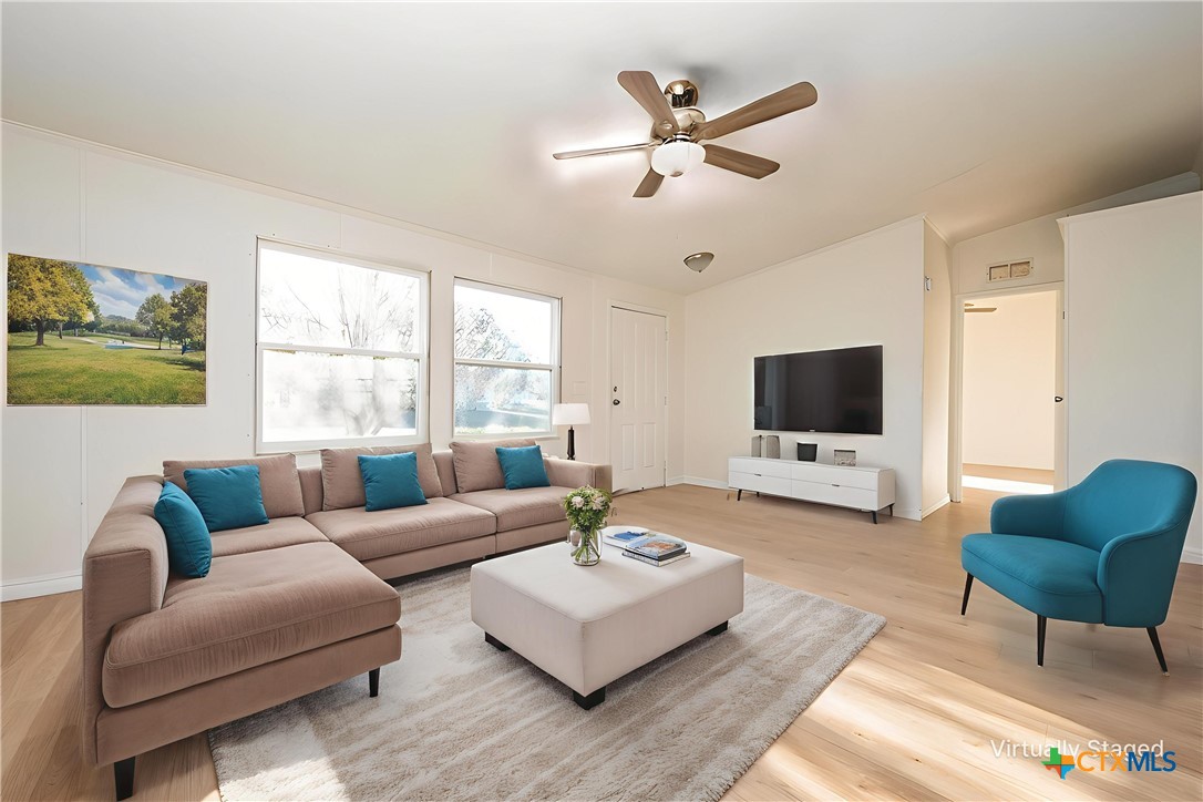 a living room with furniture a flat screen tv and a large window