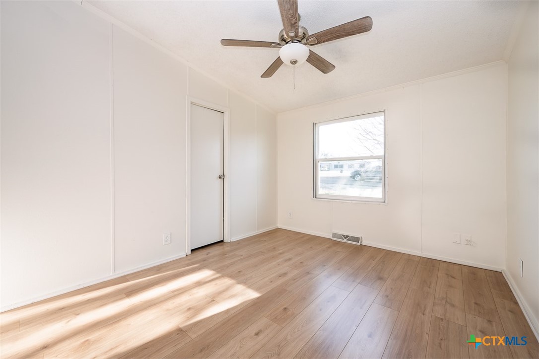 105 Grace Road Belton, TX 76513 - Photo 13 of 25 an empty room with wooden floor ceiling fan and windows