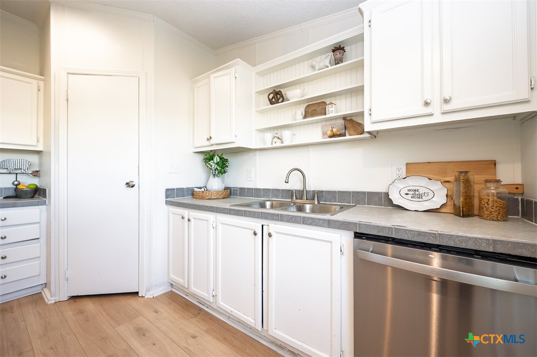 105 Grace Road Belton, TX 76513 - Photo 9 of 25 a kitchen with stainless steel appliances granite countertop a sink and wooden cabinets with wooden floor