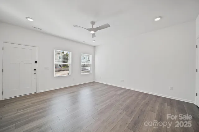 an empty room with wooden floor fan and windows