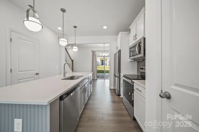 a large kitchen with kitchen island a stove a sink a center island and wooden floor
