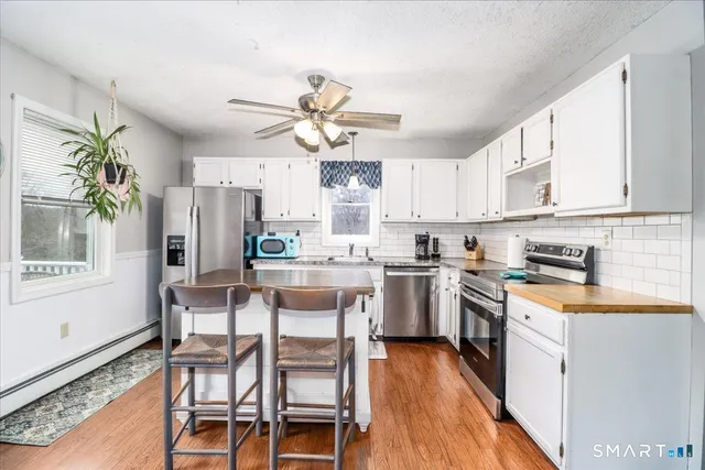 a kitchen with stainless steel appliances a dining table chairs stove and refrigerator