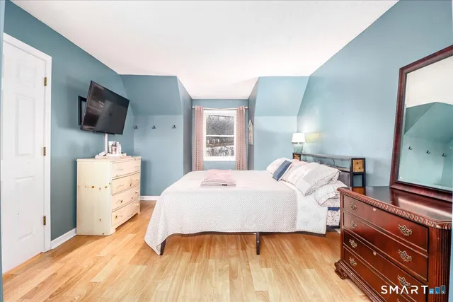 a bedroom with a bed and a flat tv screen on dresser