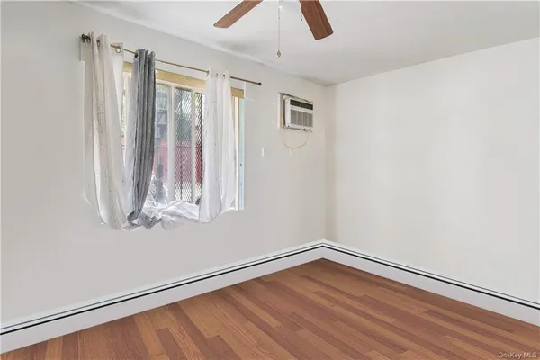 a view of an empty room with wooden floor and window