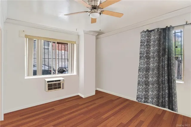 a view of an empty room with a window and wooden floor