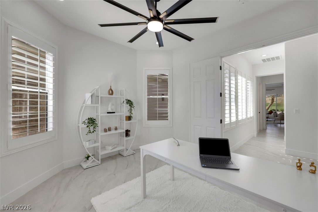 5015 Rivedro Street Las Vegas, NV 89135 - Photo 31 of 91 A well-lit home office features modern shelving, elegant flooring, and a large window with privacy shutters.