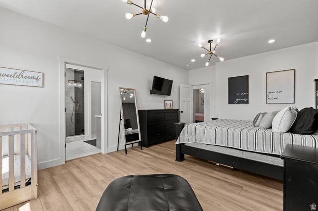 3111 South 1250 West Logan, UT 84321 - Photo 16 of 51 Spacious bedroom featuring wood-finish flooring, two modern sputnik chandeliers, recessed lighting, and a private en-suite bathroom with a glass-enclosed shower