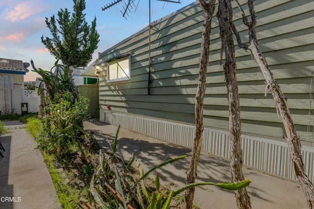 a backyard of a house with table and chairs and potted plants