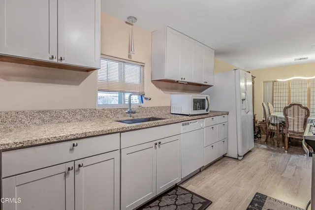 a kitchen with granite countertop white cabinets and white appliances
