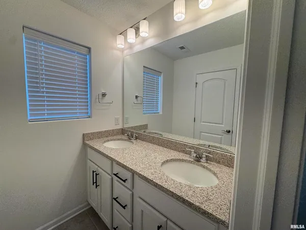 a bathroom with a granite countertop double vanity sink and mirror