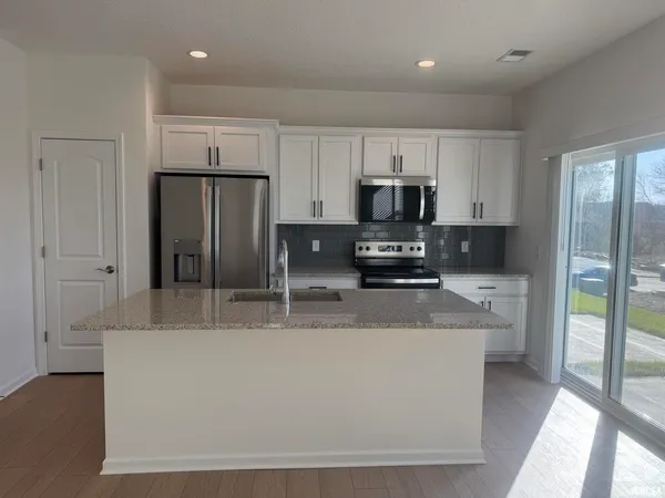 a large kitchen with stainless steel appliances granite countertop a refrigerator a sink a stove a microwave and cabinets