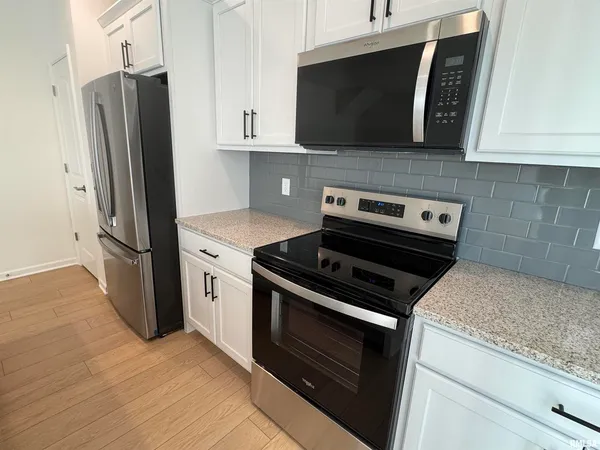 a kitchen with stainless steel appliances white cabinets and a stove a refrigerator with wooden floor