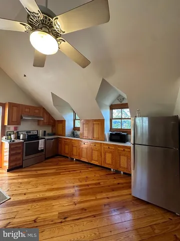 a kitchen with stainless steel appliances wooden floor and a refrigerator