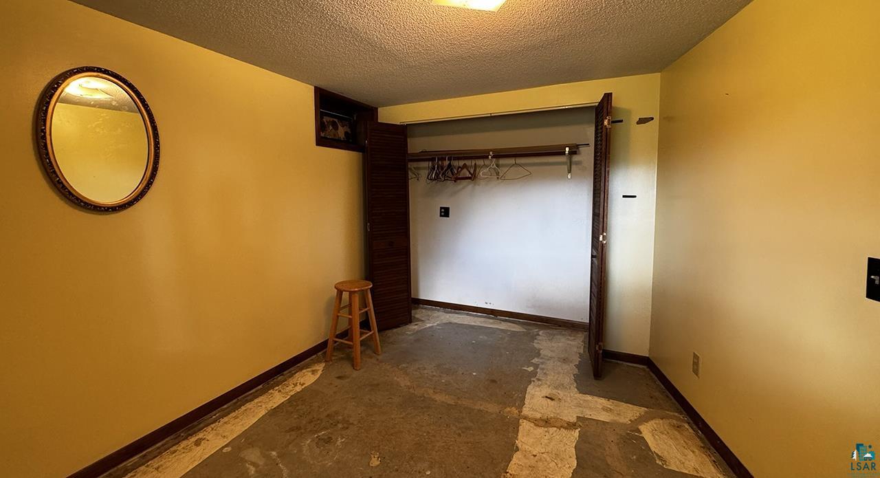 9289 Heino Road Angora, MN 55703 - Photo 22 of 37 Room featuring a closet with bi-fold doors, overhead lighting, and concrete flooring