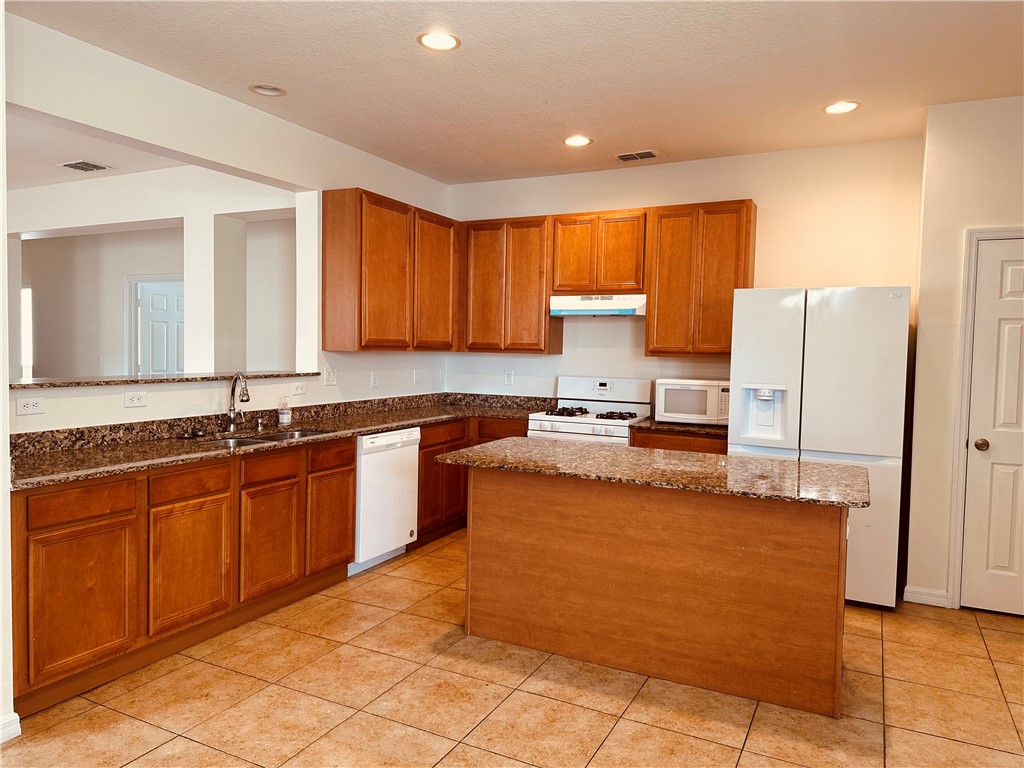 7710 15th Street Vero Beach, FL 32966 - Photo 6 of 25 a large kitchen with granite countertop a refrigerator a stove top oven and a sink